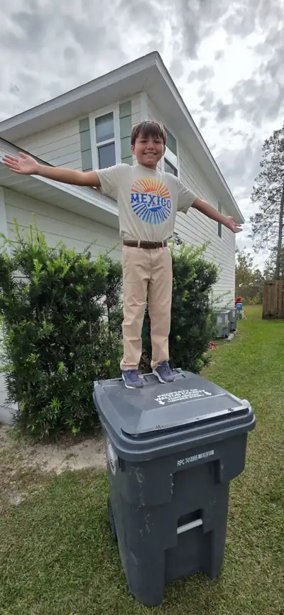 Levi standing on top of a trash can with his arms out